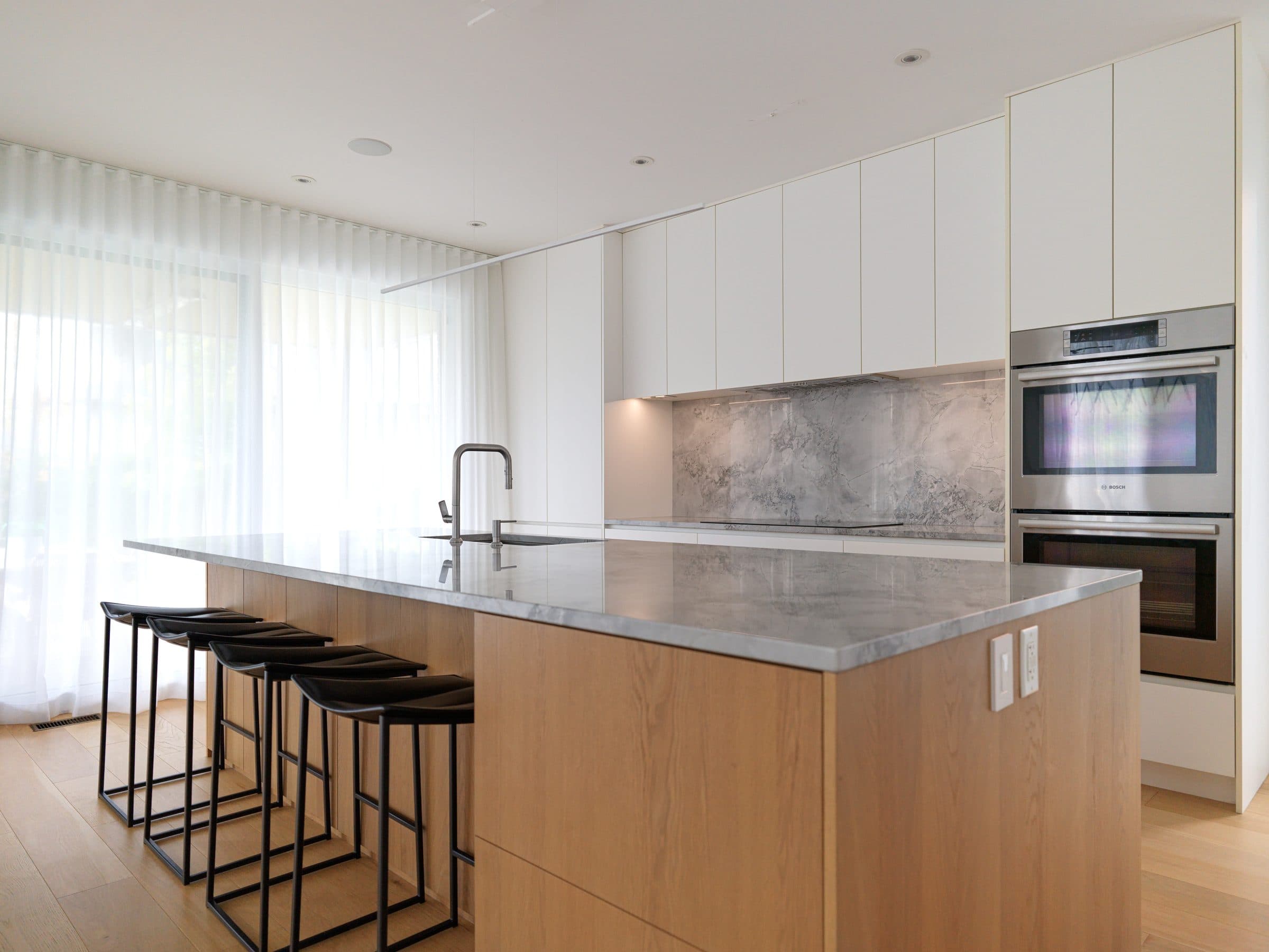 Cuisine lumineuse avec îlot central et tabourets.