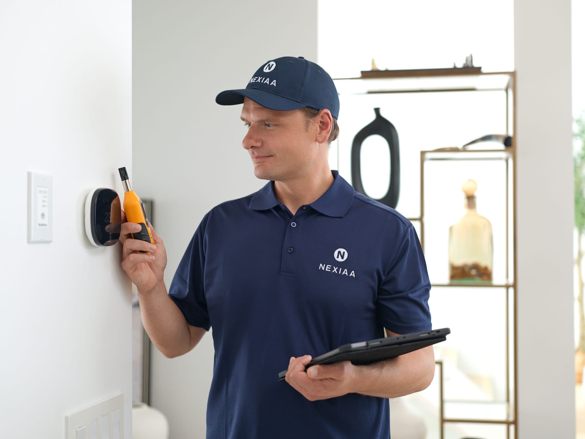 Technicien Nexiaa vérifiant le thermostat, tablette en main.